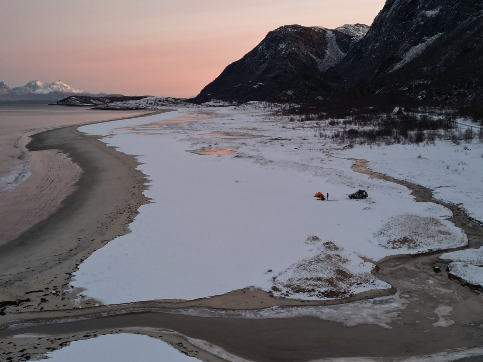 Camp on a snowy beach at dawn: a tent and the car
