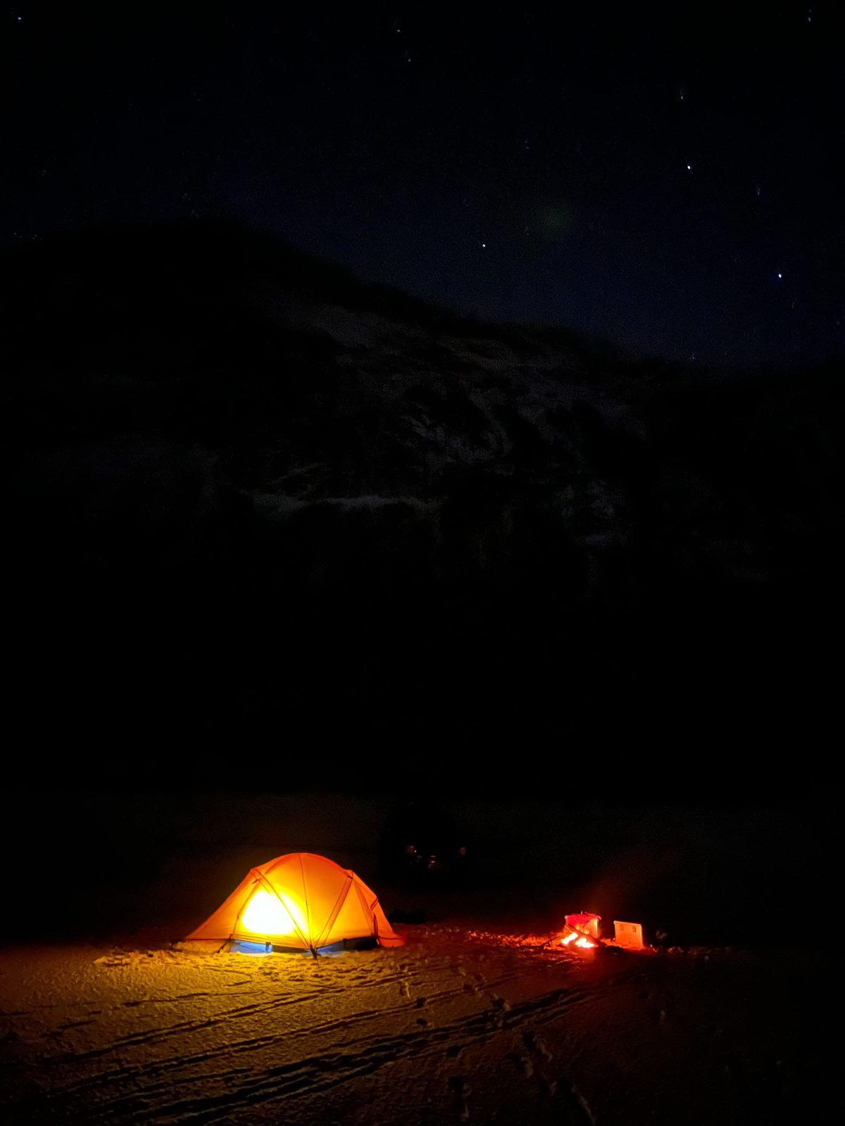 A tent glowing under the stars. Cosier than it looks. Probably